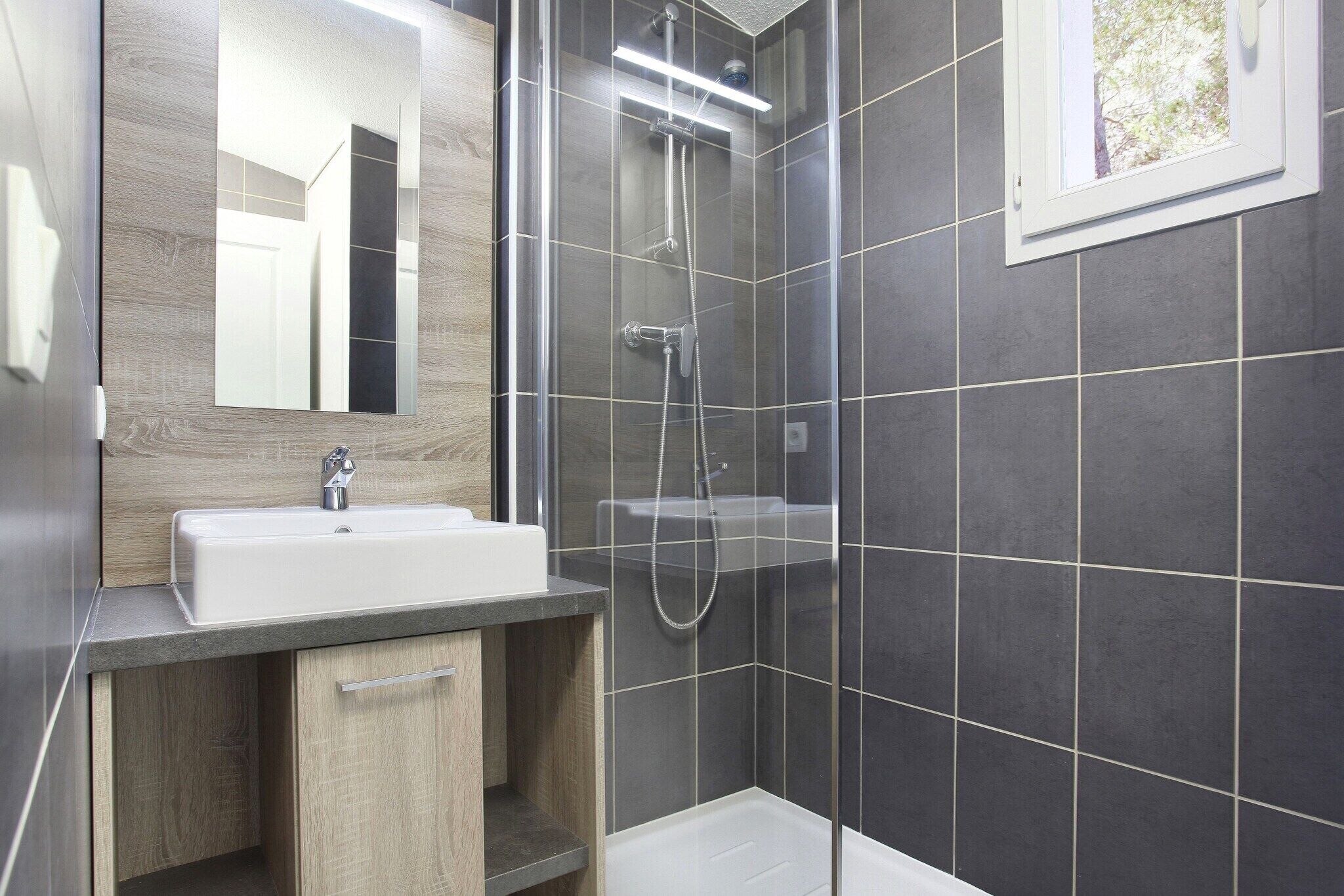 Une salle de bain moderne avec une douche, un lavabo et un miroir.