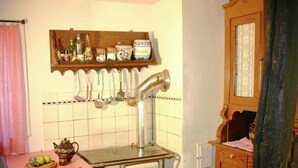 A vintage kitchen with a stove, wooden cabinets, and a tiled backsplash. - Traditionelles Ferienhaus in Hessen mit Garten (Willingshausen)