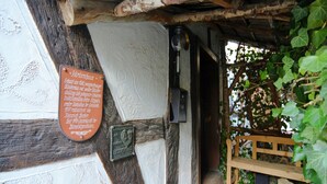 Un edificio tradizionale con travi a vista in legno, una targa con informazioni storiche e una panca rustica.