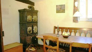 A traditional room with a wooden table, two chairs, a cabinet with clocks, and a window with a curtain. - Traditionelles Ferienhaus in Hessen mit Garten (Willingshausen)