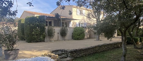 Una casa con un muro de piedra, camino de grava y un pequeño arroyo.