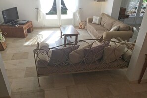 A living room with a sofa, a coffee table, a TV, and a window with curtains. - Inviting Villa with Swimming Pool (SAUMANE-DE-VAUCLUSE)