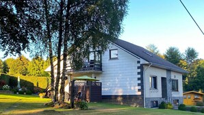 A two-story house with a sloped roof, a covered porch, and a well-maintained lawn.