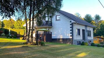 A two-story house with a sloped roof, a covered porch, and a well-maintained lawn.