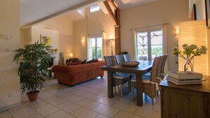 A spacious living area with a high ceiling, a dining table, and a sofa.