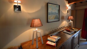 A wooden desk with a lamp, books, and a framed painting on the wall. - Holiday Home in Ardennes near Chimay Abbey (Nismes Viroinval)