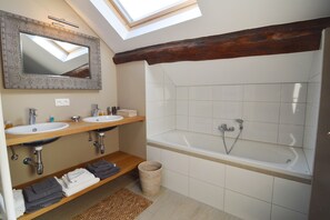 A modern bathroom with two sinks, a large bathtub, wooden beams, and a skylight. - Holiday Home in Ardennes near Chimay Abbey (Nismes Viroinval)