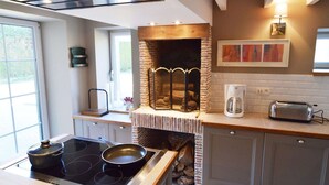 A modern kitchen with a built-in stove, a brick fireplace, and a coffee maker. - Holiday Home in Ardennes near Chimay Abbey (Nismes Viroinval)