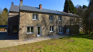 A stone house with a paved driveway and a grassy yard. - Holiday Home in Ardennes near Chimay Abbey (Nismes Viroinval)