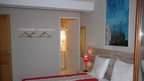 Une chambre à coucher avec un lit, une table de chevet, une lampe, un tableau et un porte-manteau.