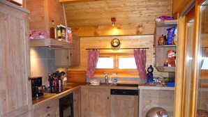 Une cuisine en bois avec une machine à café, un évier et une horloge au mur.