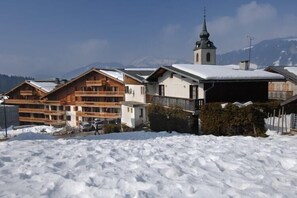 Ein mit Schnee bedecktes Gebäude mit einem Kirchturm im Hintergrund.