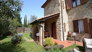 Una casa de piedra con un patio, muebles de exterior y un jardín.