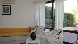 A living room with a sofa, two wicker chairs, a coffee table, and a large window with curtains.