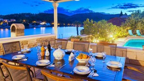 An outdoor dining area with a view of a lake and mountains at dusk. - Villa in Selca with Pool near Adriatic Sea (Sumartin)
