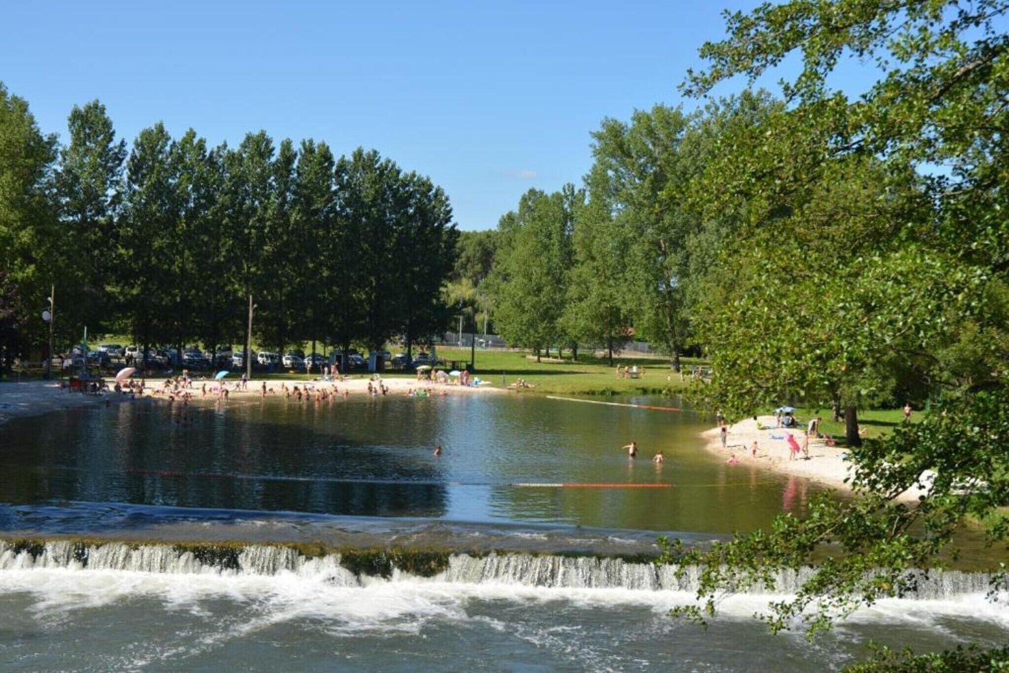 Un parc avec un étang, des arbres et une petite île où se trouvent des personnes.