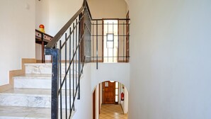 A staircase with marble steps and a metal railing leading to an upper floor.