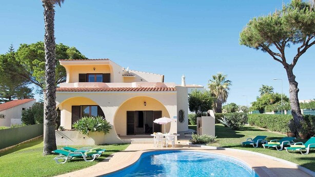 A two-story house with a swimming pool, outdoor seating, and a well-maintained garden.