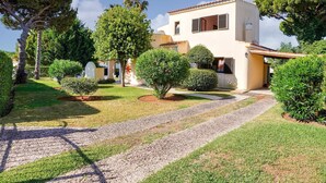 A two-story house with a gravel driveway leading to the entrance, surrounded by well-maintained lawns and various trees.