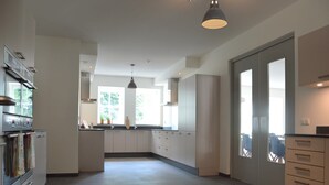 Eine moderne Küche mit Kochinsel, integrierten Geräten und großen Fenstern für natürliches Licht.