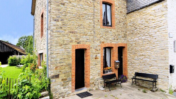 A stone building with two visible windows and a bench outside.