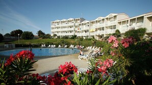 A hotel with a pool, lounge chairs, and a garden with red flowers. - Coastal Getaway with Pool (Fouras)