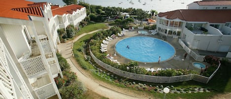 Ein Resort mit einem zentral gelegenen Schwimmbad, umgeben von Liegestühlen und einem angelegten Garten.