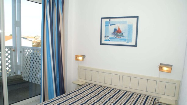 A bedroom with a bed, a view of the outside, and a framed picture on the wall. - Coastal Getaway with Pool (Fouras)