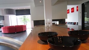 Cocina moderna con encimera de madera, tazones negros y una zona de estar roja.