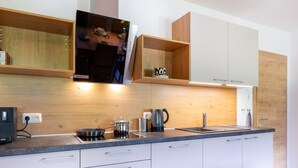 Une cuisine moderne avec des armoires blanches, un plan de travail en bois et des étagères intégrées.