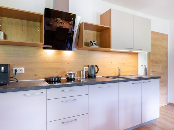 Una cocina moderna con armarios blancos, encimera de madera y estanterías empotradas.