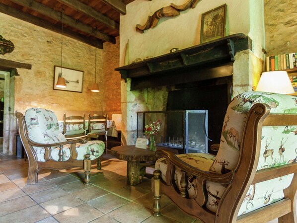 A cozy room with a fireplace, wooden furniture, and stone walls.