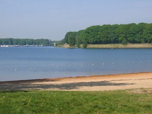 A lake with a sandy beach and grassy area in the foreground.