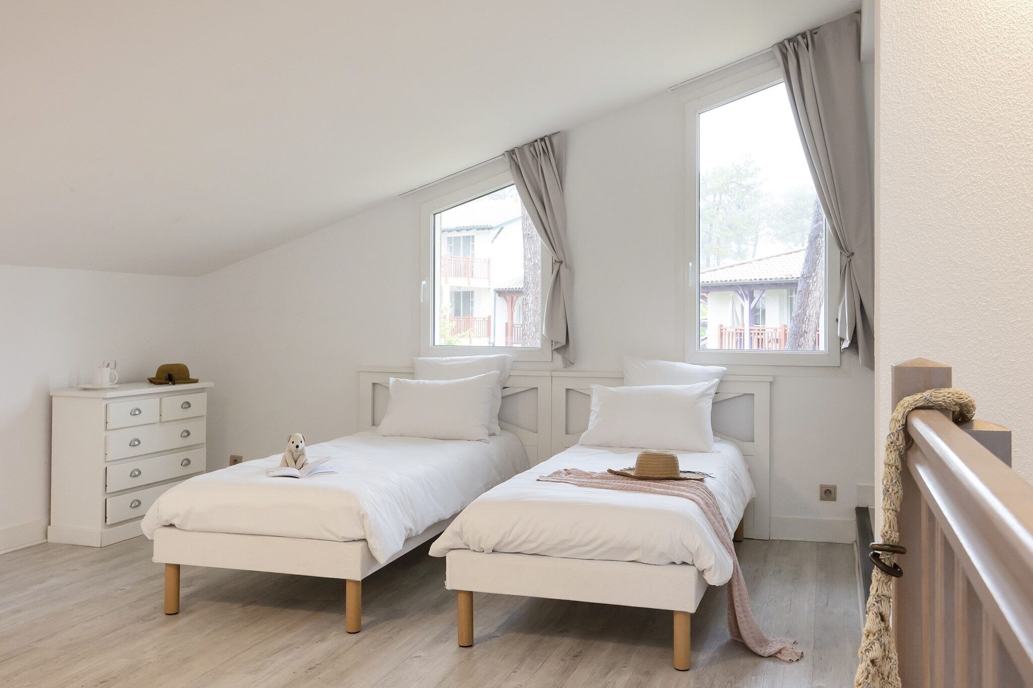 A bedroom with two beds, a dresser, and a window with curtains.