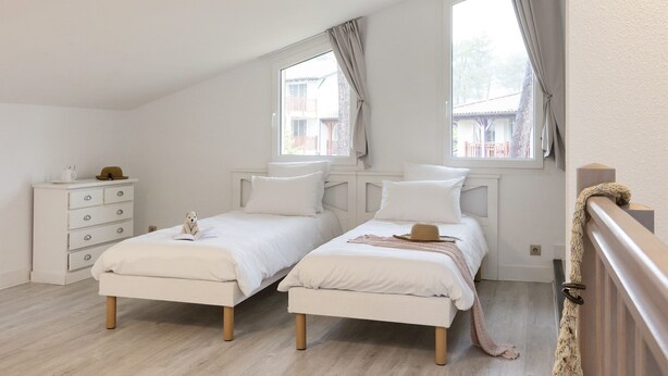A bedroom with two beds, a dresser, and a window with curtains. - Villa in France by Golf Course with Pool (Gujan Mestras)
