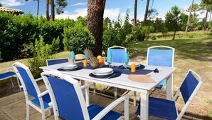 An outdoor table set with chairs, plates, cutlery, and a fruit bowl. - Villa in France by Golf Course with Pool (Gujan Mestras)