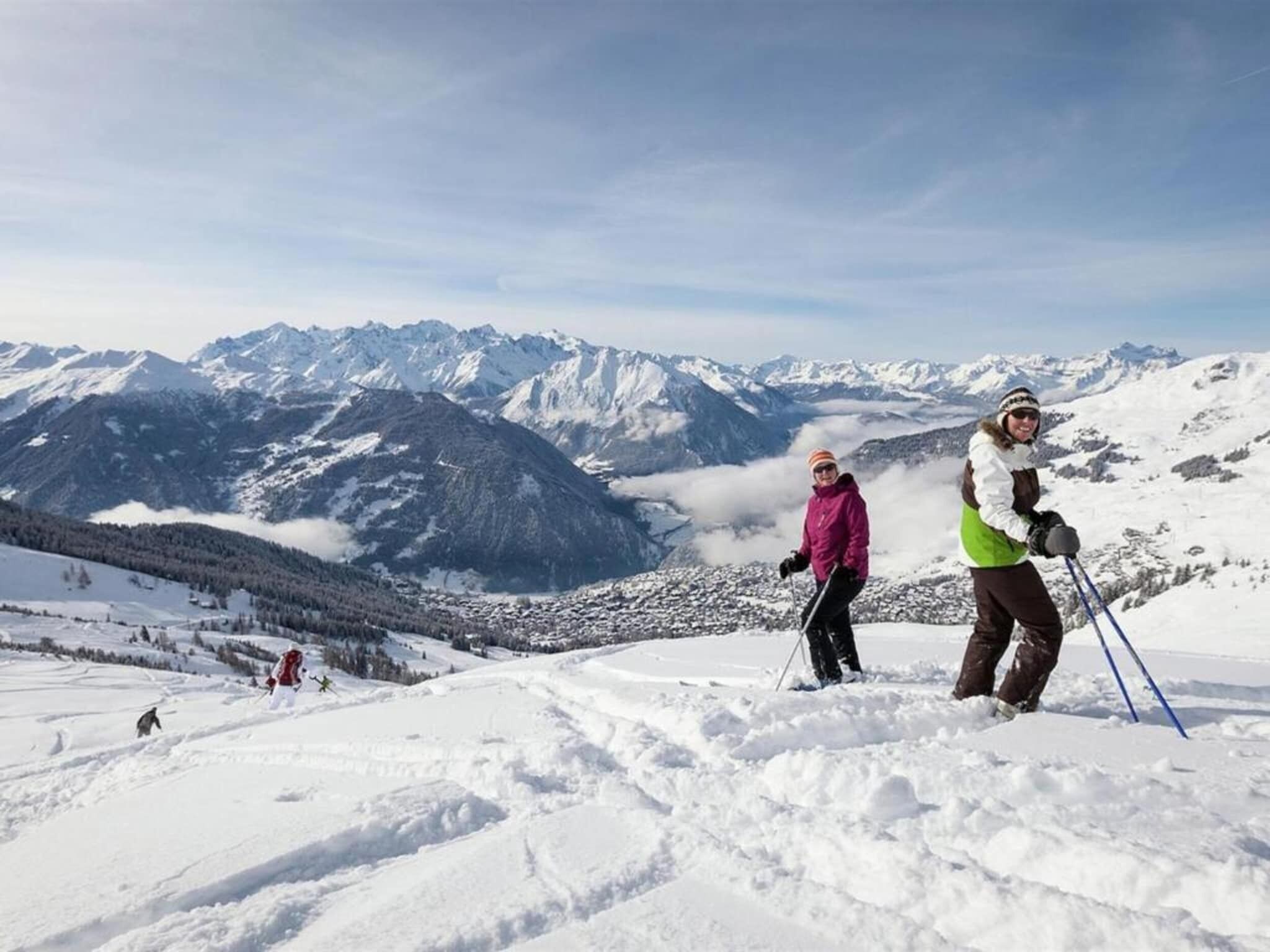 A snowy mountain landscape with skiers.
