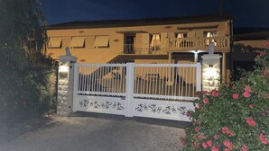 A two-story building with a white gate, a balcony, and a statue.