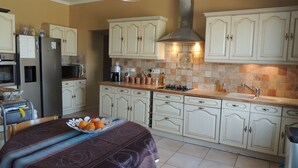 A kitchen with white cabinets, a stainless steel range hood, and a dining area with a table set for two.