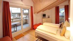 Et soveværelse med træloft, en seng, et fjernsyn og en skydedør, der fører til en balkon.