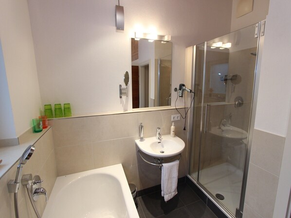 Un baño moderno con bañera, lavamanos y cabina de ducha de vidrio.