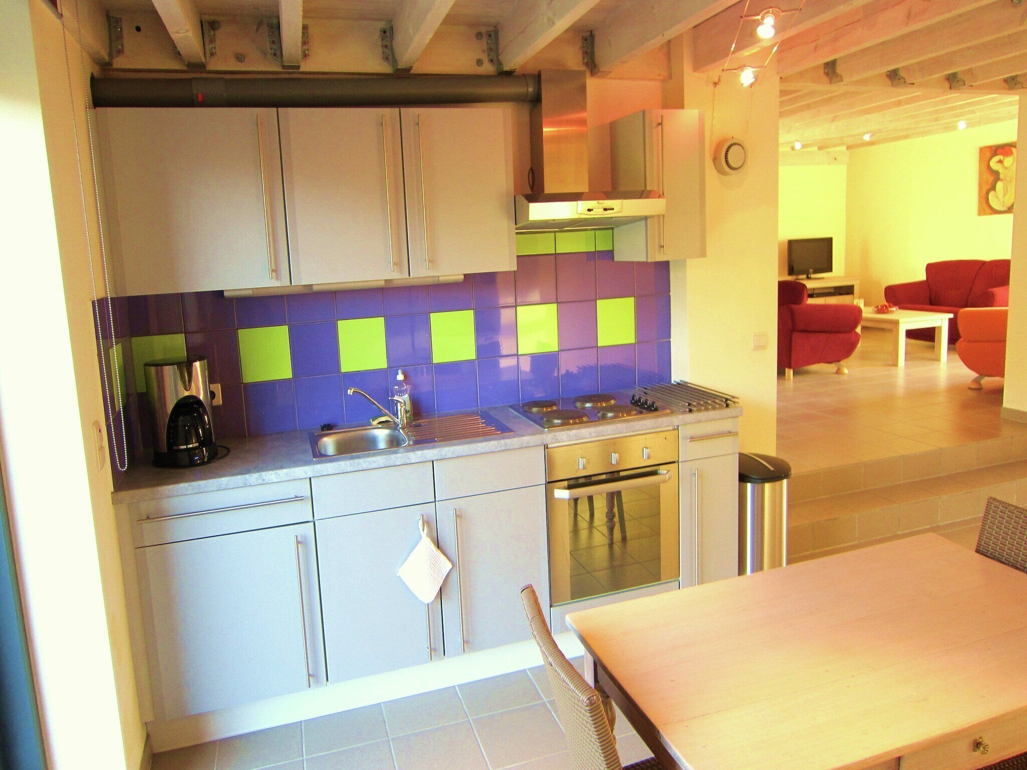 A modern kitchen with a gas stove, sink, and a dining area with a table and chairs.