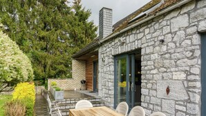 A stone building with a wooden deck and a table with chairs.