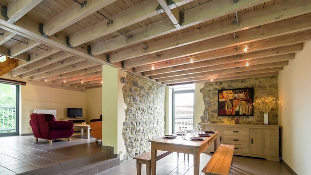 A modern interior with a dining area, a stone accent wall, and a television in a living space.