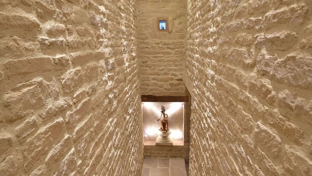 A narrow stone corridor with a statue at the end. - Manor in Normandy with Spa and Pool (Lantheuil)
