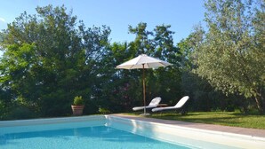 Piscina com espreguiçadeiras e guarda-sol.