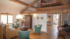 A spacious living room with wooden beams, a staircase, and a view to the outside. - Cottage in Dordogne with Accessible Terrace (Roussines)