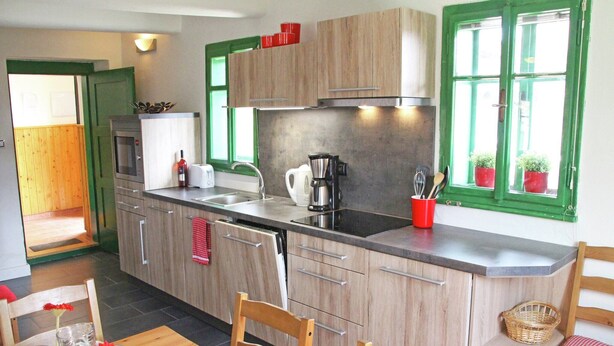 A modern kitchen with wooden cabinets, a stainless steel sink, and a dining area with a wooden table and chairs.