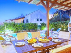 An outdoor dining area with a pool, lounge chairs, and a wooden pergola. - Beautiful villa with spacious terrace and private swimming pool, on the Croatian island of Hvar (Hvar)