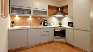 A modern kitchen with white cabinets, a built-in oven, and a coffee maker. - Beautiful villa with spacious terrace and private swimming pool, on the Croatian island of Hvar (Hvar)